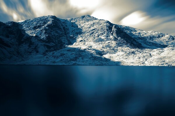 The blue expanse of the sea against the background of snow-capped mountains