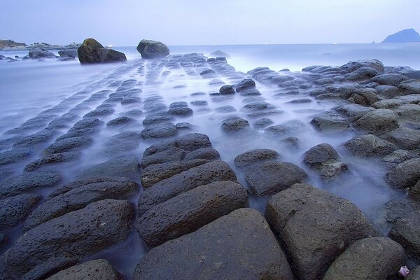 Mer avec des pierres dans le brouillard