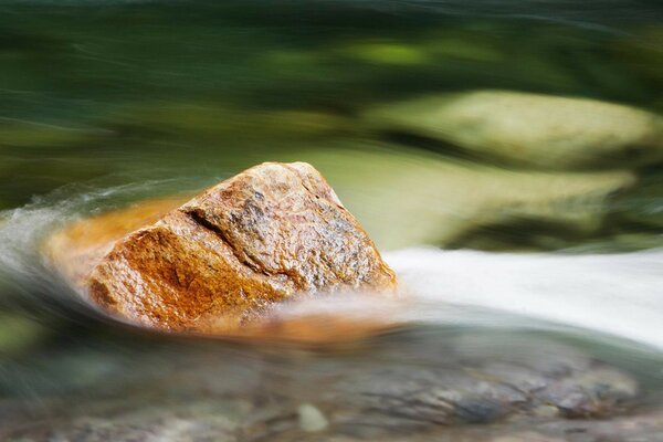 A large stone in the water against the stream