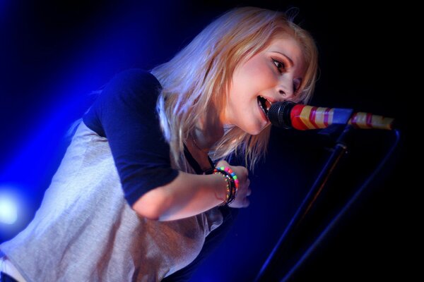 La ragazza canta in microfono colorato