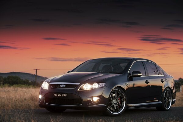 A black glancing Ford at sunset