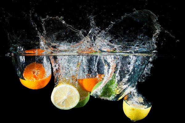 Citrus fruits - orange, lemon and lime fall into the water with a splash