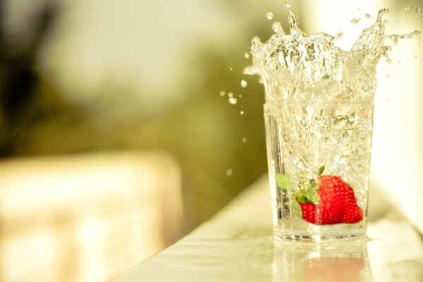 Erdbeeren mit Streuseln fallen in ein Glas