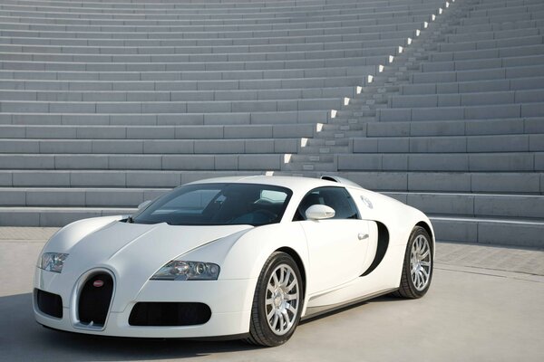 Белый суперкар bugatti veyron на фоне бетонных ступеней