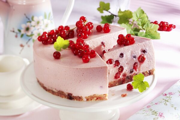 Pink cheesecake with red currants on the table