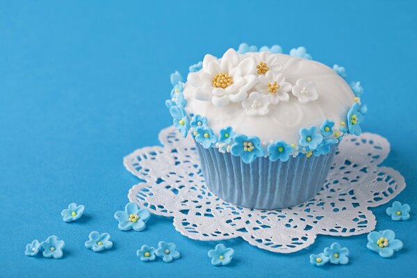 Кекс с украшениями в виде цветочков на голубом фоне