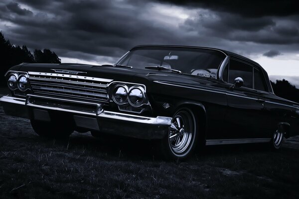 A 1967 chevrolet car is parked near a forest