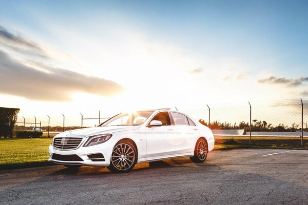 Weißer Mercedes auf Sonnenuntergang Hintergrund