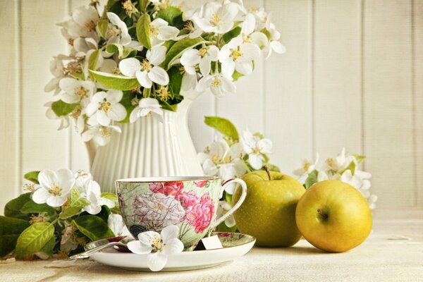 Flores en un jarrón con una taza de té