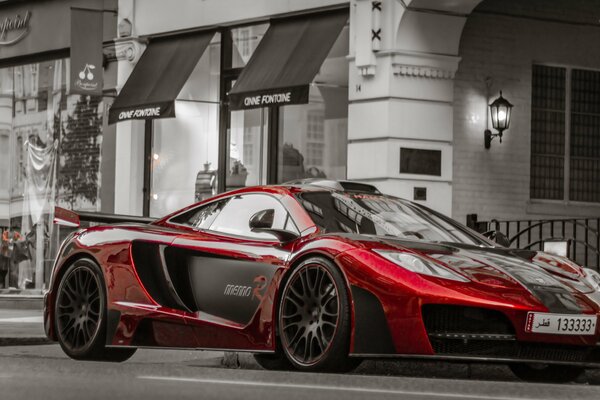 Coche rojo contra un edificio gris