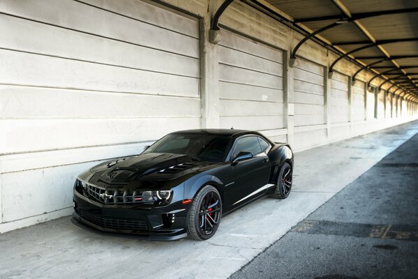 A black Chevrolet Camaro is parked at the garages