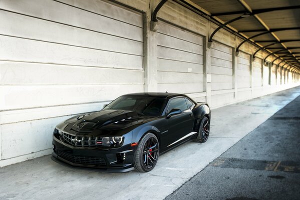 Une Chevrolet Camaro noire se tient dans les garages