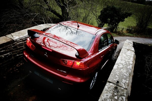 Mitsubishi from the rear view on a stone bridge in front of a country road