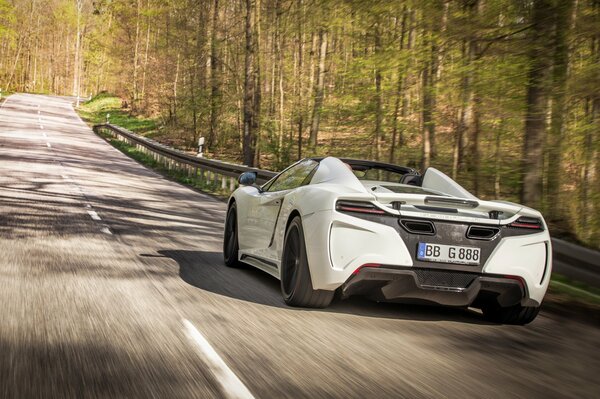 El coche gemballa conduce por la carretera cerca del bosque