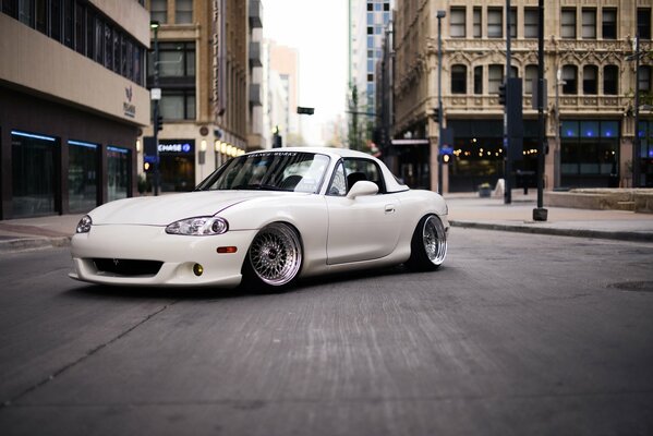 Weißer Mazda miata auf Stadtstraße Hintergrund