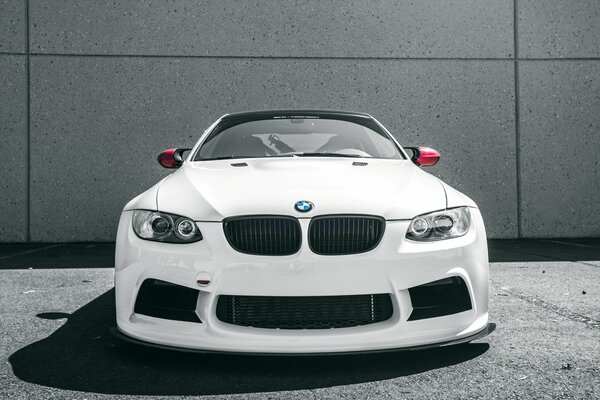 Białe BMW M3 na tle ściany