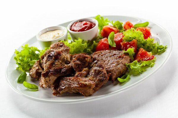 Carne asada en un plato blanco con ensalada de verduras y salsas