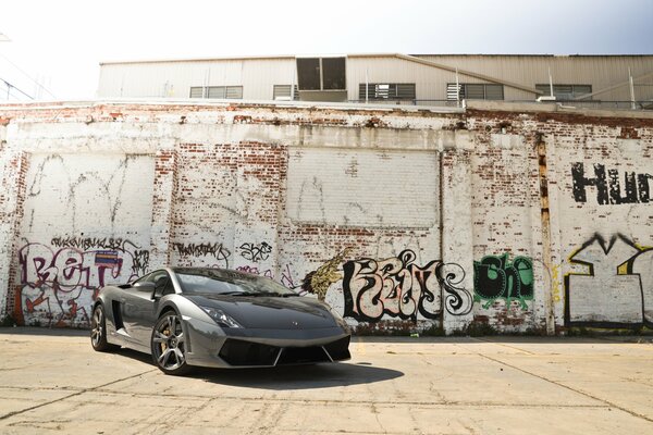 Lamborghini su sfondo muro di mattoni con graffiti