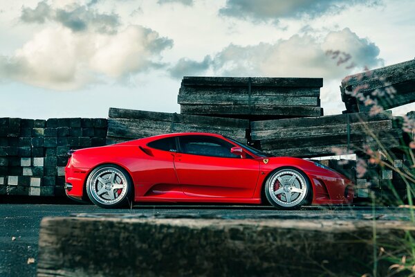 Red ferrari f430 with cast wheels against the sky and clouds