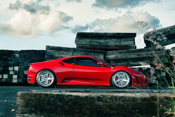 Ferrari F430 rossa con ruote in lega su uno sfondo di cielo e nuvole