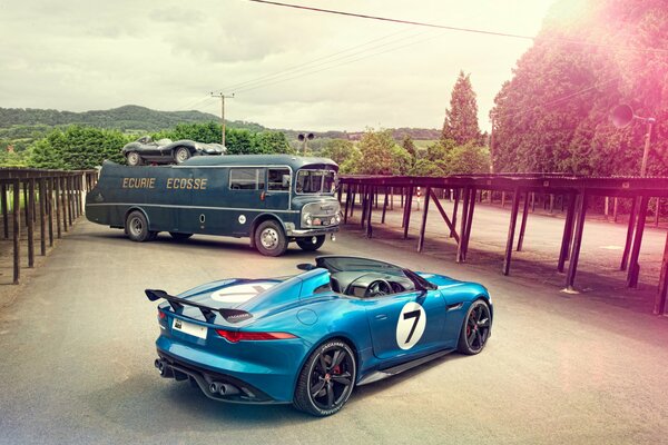 Niebieski Jaguar i autobus na tle miasta