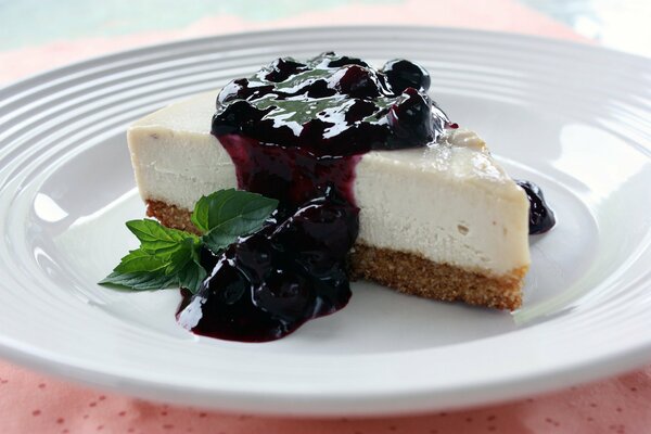 A piece of cheesecake with cherry jam and mint leaf