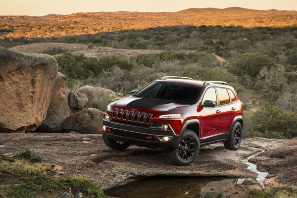 JEEP CHEROKEE EN LAS ROCAS EN LOS RAYOS DEL ATARDECER