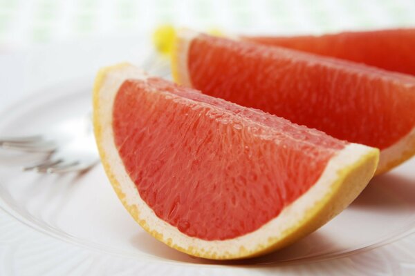 Grapefruit slices on a plate on a white background