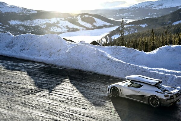 Blanc königsegg Agera se précipite sur une route enneigée dans les montagnes