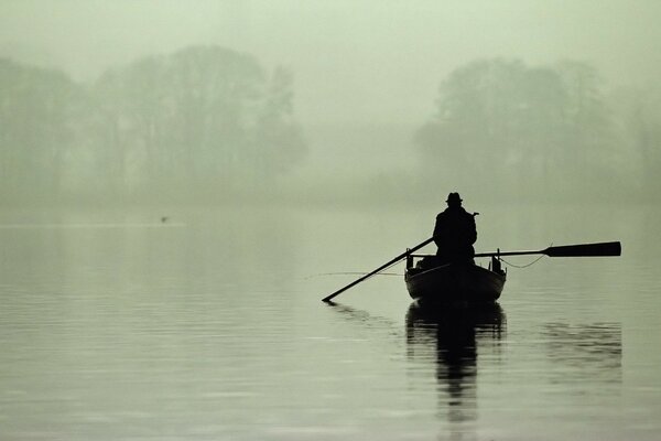 Nebbia sul lago. pescatore in barca