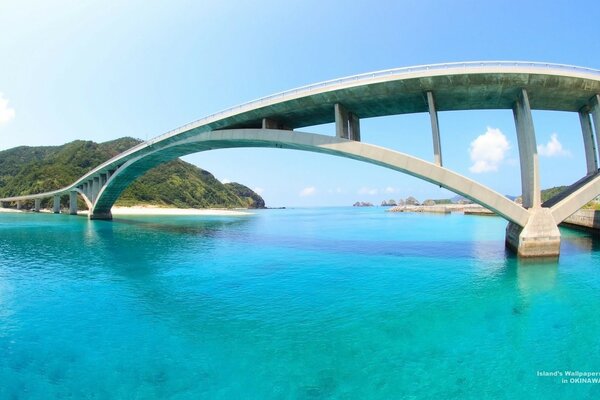 Una isla con un puente sobre el mar con montañas