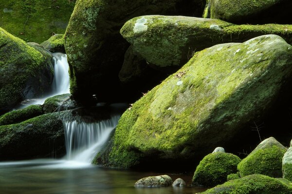 Landschaft mit Wasserfall und moosigen Felsbrocken