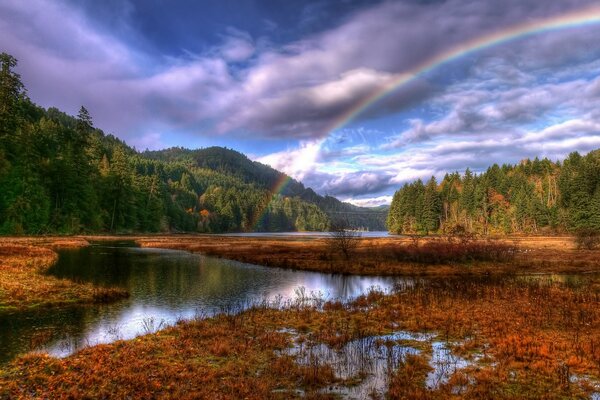 Arcobaleno sullo sfondo di una foresta di nuvole e un fiume che scorre