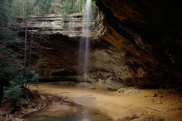 Bäume am Wasserfall über einer Klippe