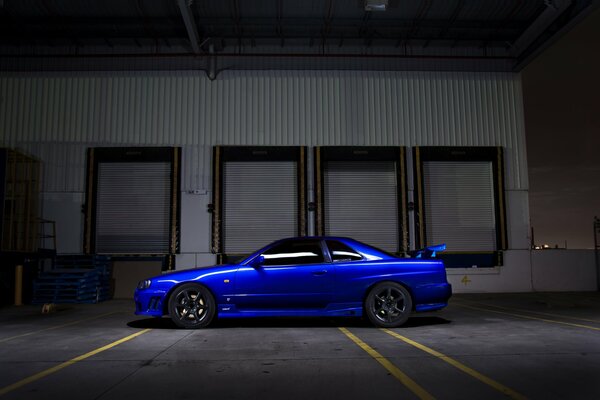 The Nissan r34 blue car is standing in the dark on the street