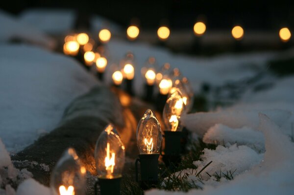 A chain of light bulbs on white snow