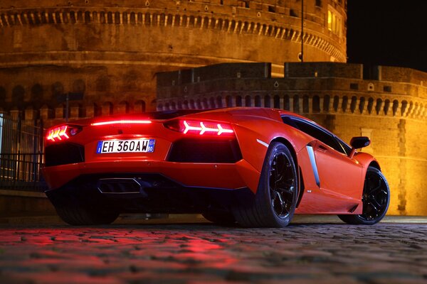 Red lamborghini aventador lp 700-4 on the background of paving stones and brick walls