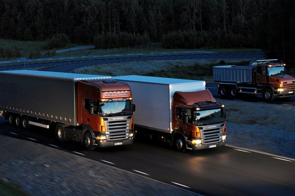 Three trucks driving on night roads