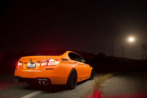 Headlights in the night of an orange BMW on the road