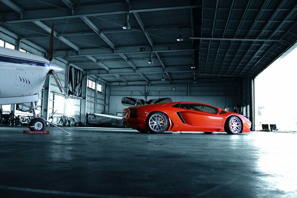 Voiture orange lamborgini aventador dans le hangar