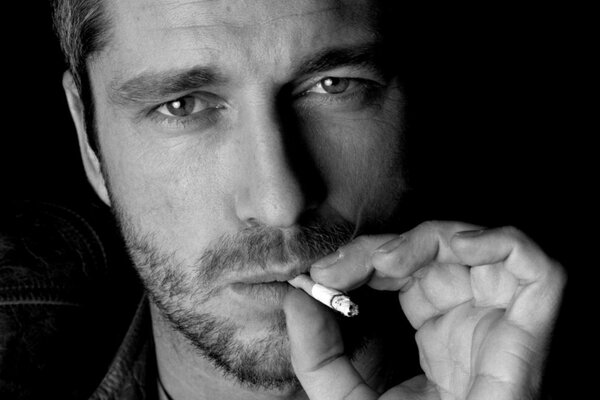 A man with stubble and a cigarette in his mouth