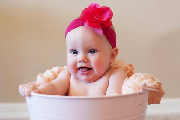 A child with a red bow on his head in a basin