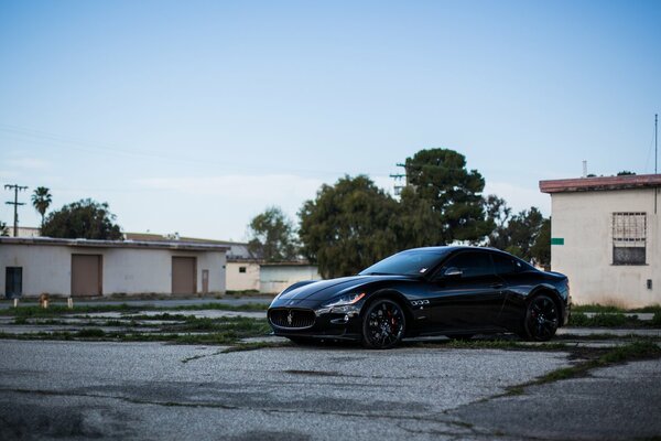 Gdzieś za domami stoi czarny Maserati na czarnych dyskach elegancki widok z boku