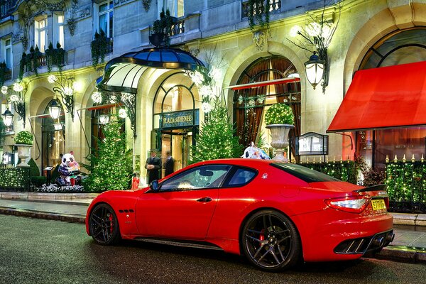 Maserati w kolorze czerwonym przy luksusowym budynku w nocy