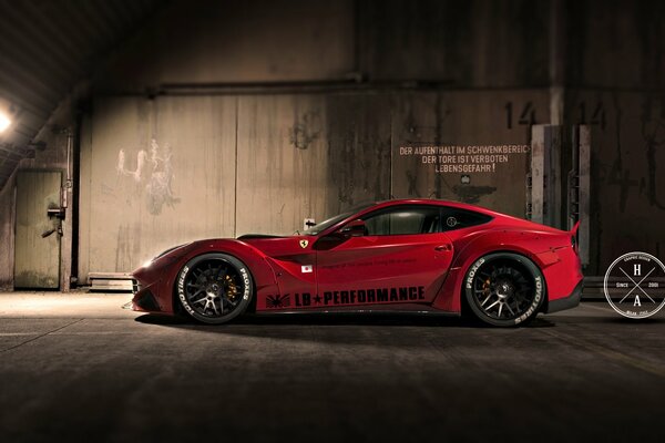 A red stylish Ferrari stands in a dark hangar