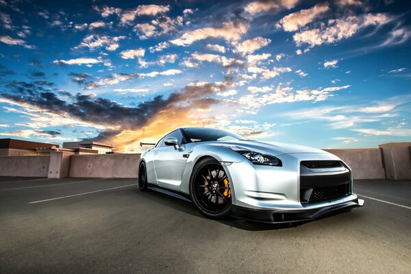 Nissan R35 plateado en el fondo de una hermosa puesta de sol