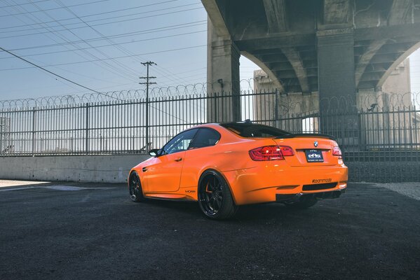 Orange BMW behind a barbed wire fence