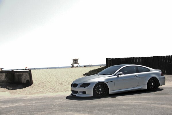 Silver BMW M6 under the sky on the beach