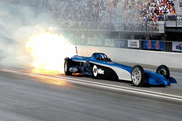 Fiery afterburner of a blue racing car on the track