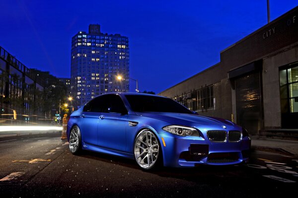 Un BMW azul nocturno se encuentra en la carretera de la ciudad